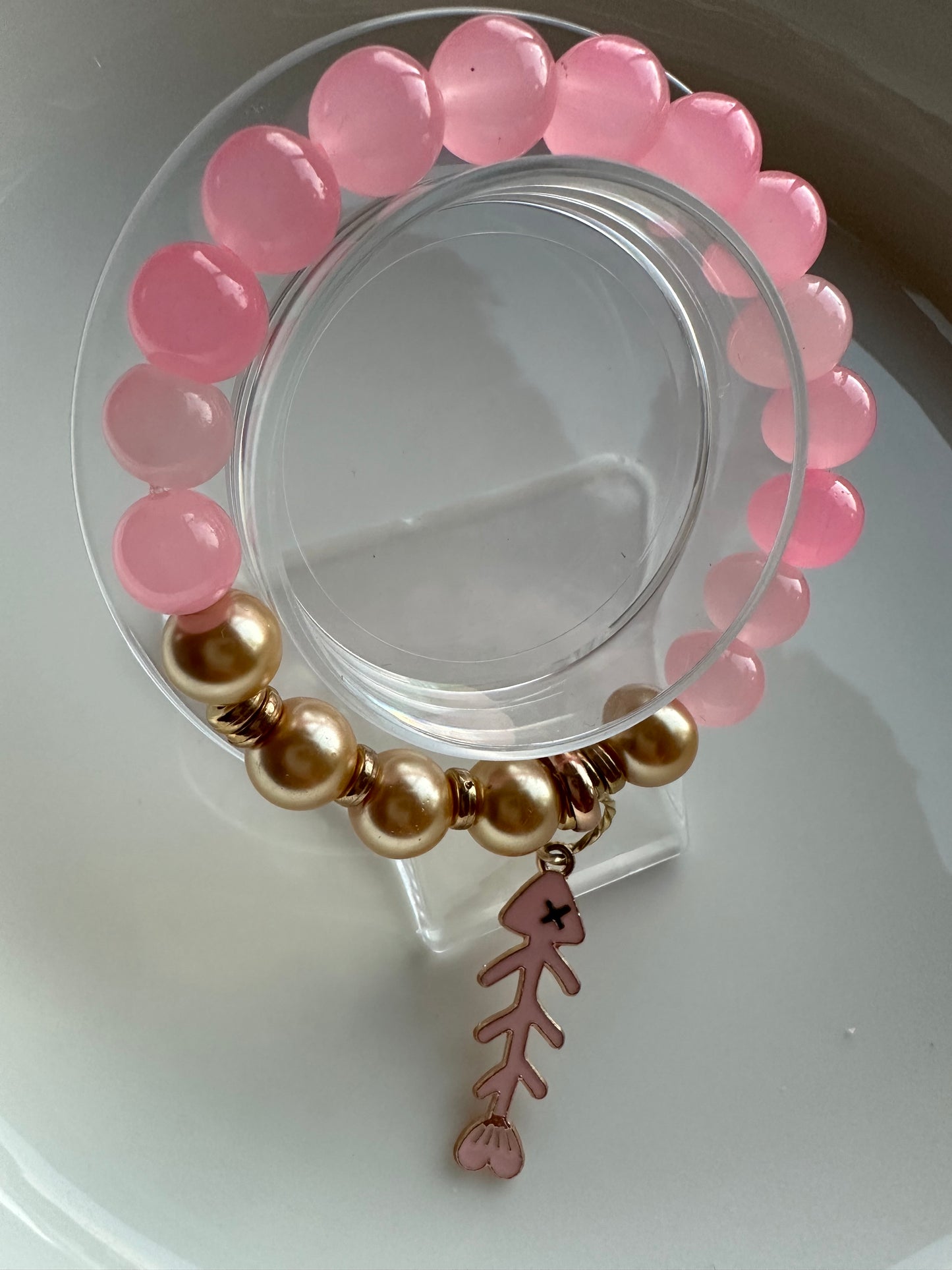 Pink and gold bracelet with a fish charm.