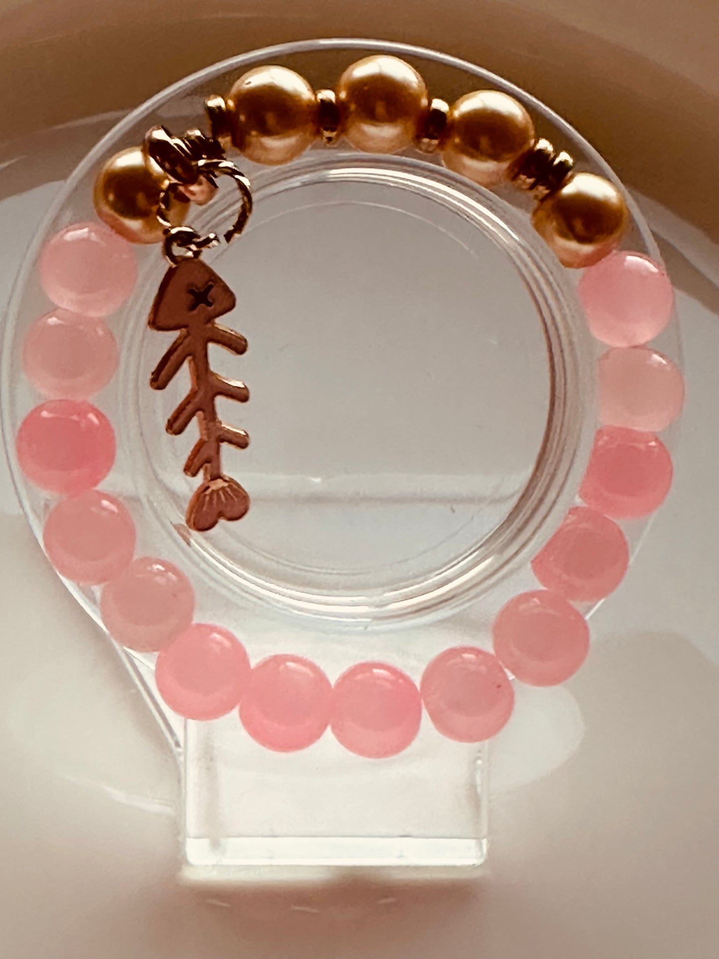 Pink and gold bracelet with a fish charm.
