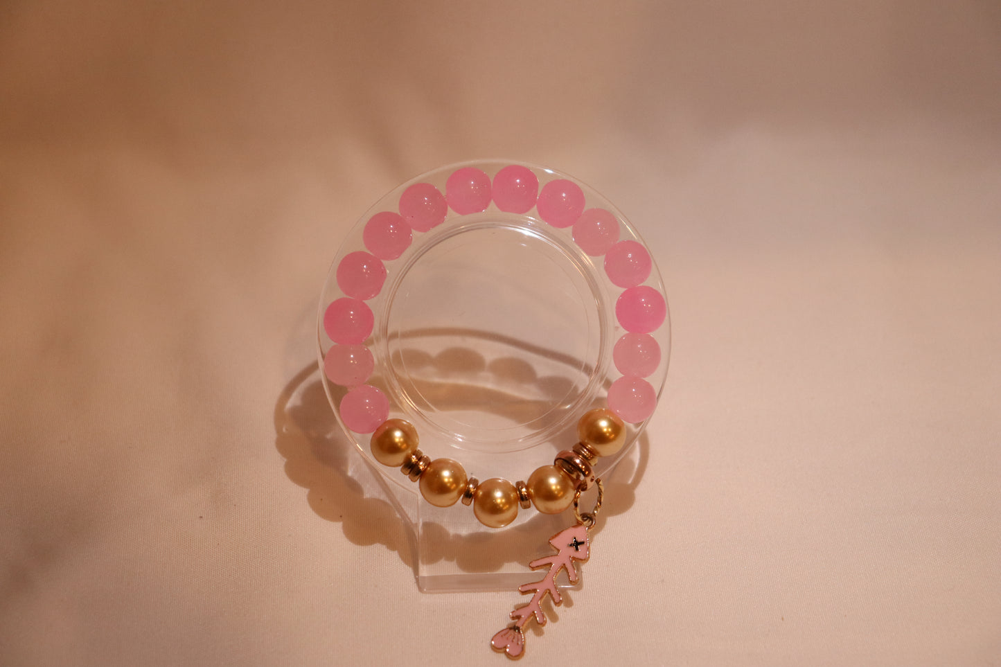 Pink and gold bracelet with a fish charm.