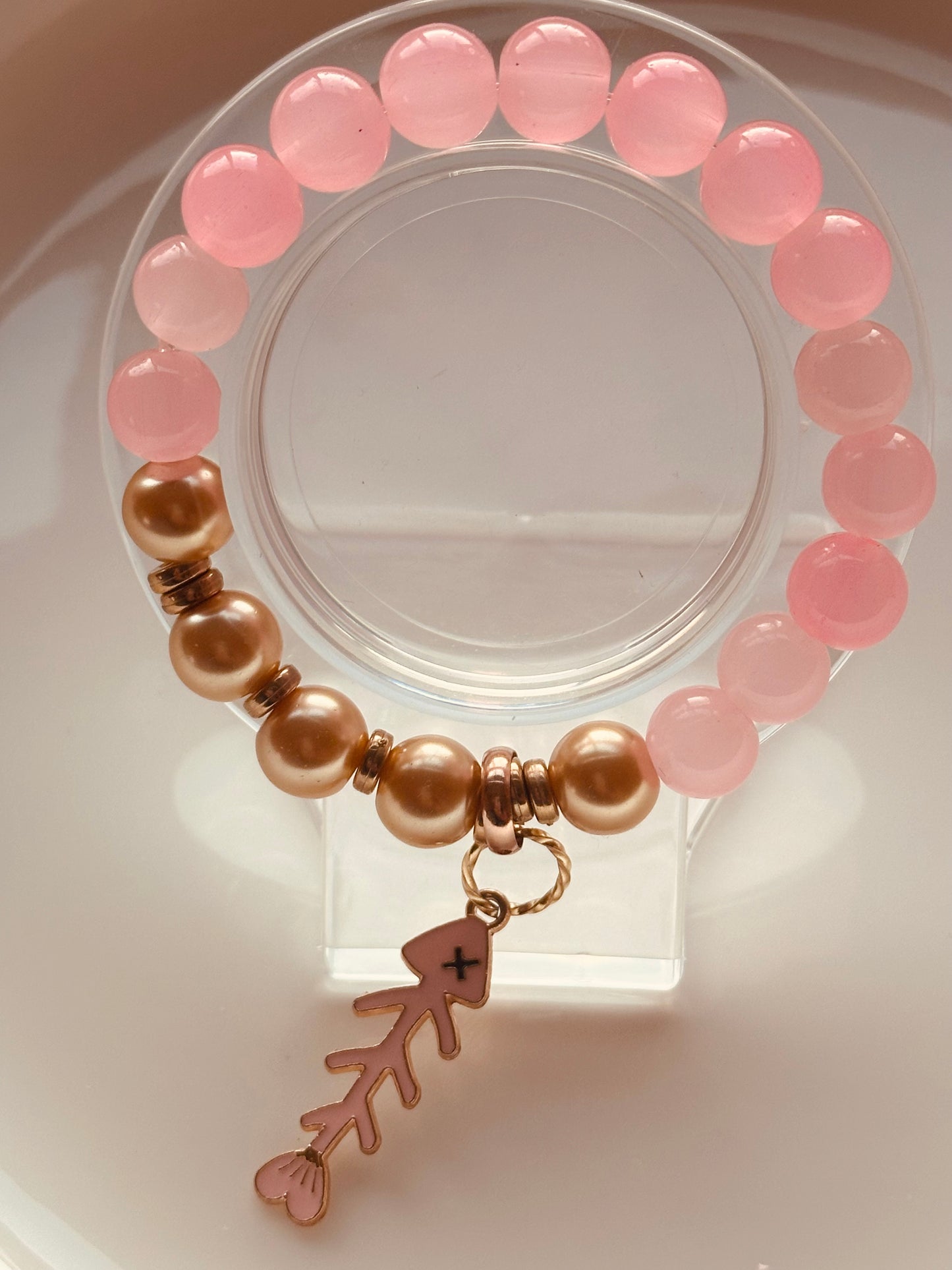 Pink and gold bracelet with a fish charm.